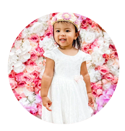 girl toddler wearing white dress in front of flowers