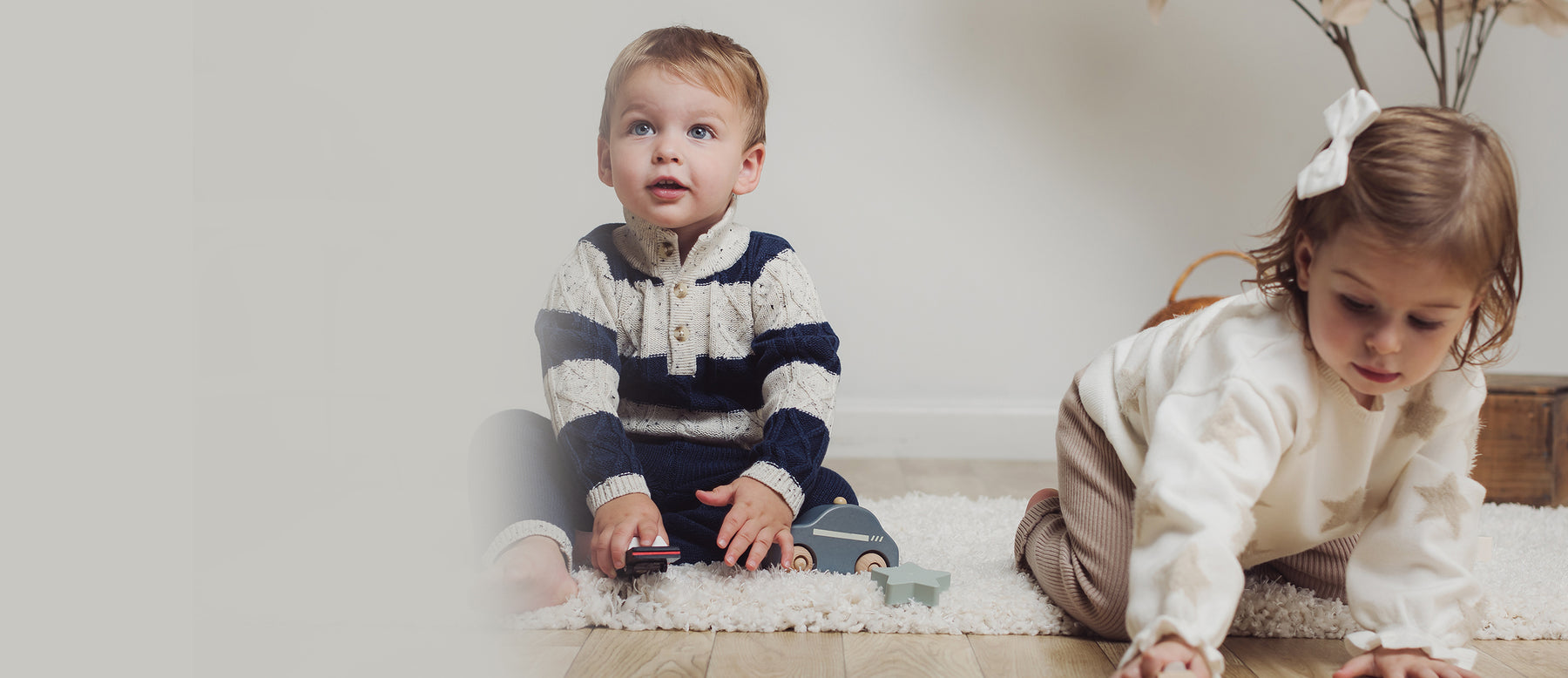 boy and girl toddler sitting on white rug